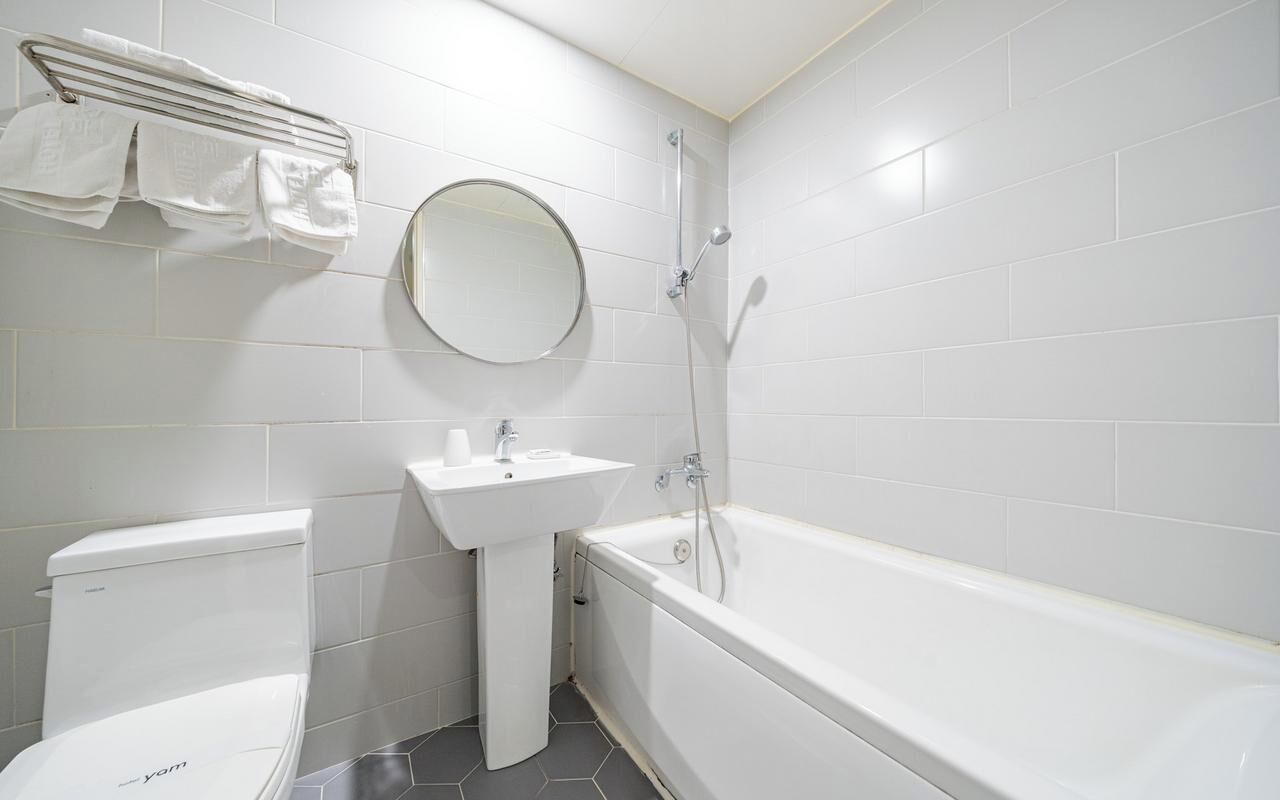 Ein Badezimmer mit Toilette, Waschbecken, Spiegel und Badewanne.
