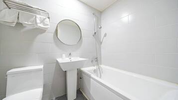 Ein Badezimmer mit Toilette, Waschbecken, Spiegel und Badewanne.