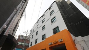 A multi-story building with a prominent orange and white facade, featuring a hotel sign.