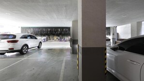 A parking garage with concrete pillars, white cars, and a visible exit.