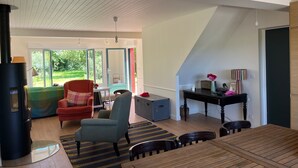 A living room with a fireplace, a dining area, and a view of the garden through open doors. - A very pleasant house with a beautiful garden, located 500 m from the harbor and the beach in Le Crotoy (Le Crotoy)