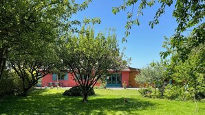 A red building with a green door, surrounded by a grassy area with trees. - A very pleasant house with a beautiful garden, located 500 m from the harbor and the beach in Le Crotoy (Le Crotoy)