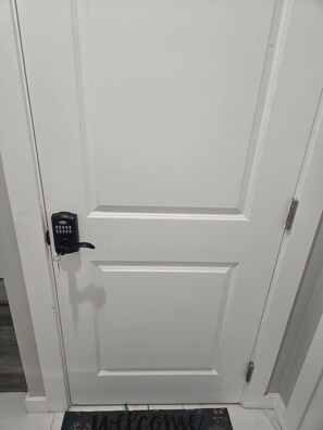 A white door with a keypad lock and a doormat with 'WELCOME' written on it. - Relax in this beautiful ,modern 2-bedroom basement suite in a quiet neighborhood (Edmonton)