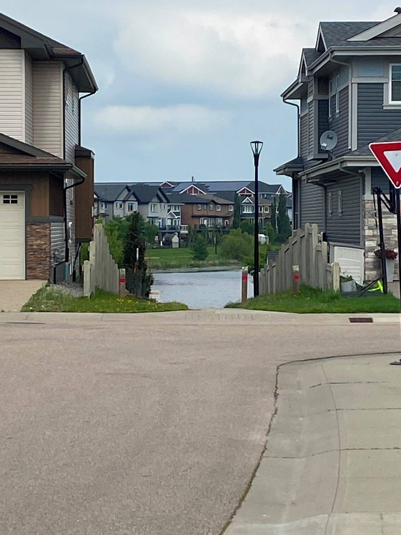 A residential street with houses, a river, and a traffic sign.