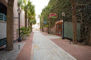 A narrow alleyway with a brick pathway, palm trees, and a building with a sign that reads 'Micheals.' - Charming downtown apartment just steps to King Street (Charleston)