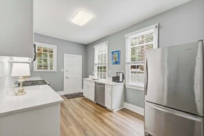 A kitchen with a refrigerator, stove, sink, and white cabinetry. - Charming downtown apartment just steps to King Street (Charleston)