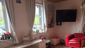 Ein Wohnzimmer mit einer weißen Unterhaltungseinheit, einem roten Sofa und einem an der Wand montierten Fernseher.