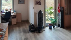 Ein Zimmer mit Holzboden, einem Schreibtisch mit Stuhl, einem Heizkörper und einem Blumentopf.