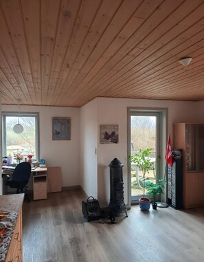 A room with a wooden ceiling, a desk with a chair, a radiator, and a potted plant. - A charming, child-friendly house/holiday home. (Øster Assels)