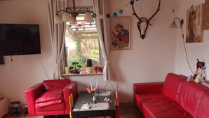 Ein Wohnzimmer mit roten Sofas, einer Holzbalkendecke, einem Fernseher und einem Fenster mit Vorhängen.
