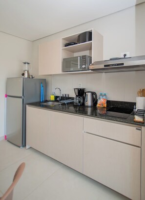 Eine moderne Küche mit Kühlschrank, Mikrowelle, Toaster, Wasserkocher und Kaffeemaschine.