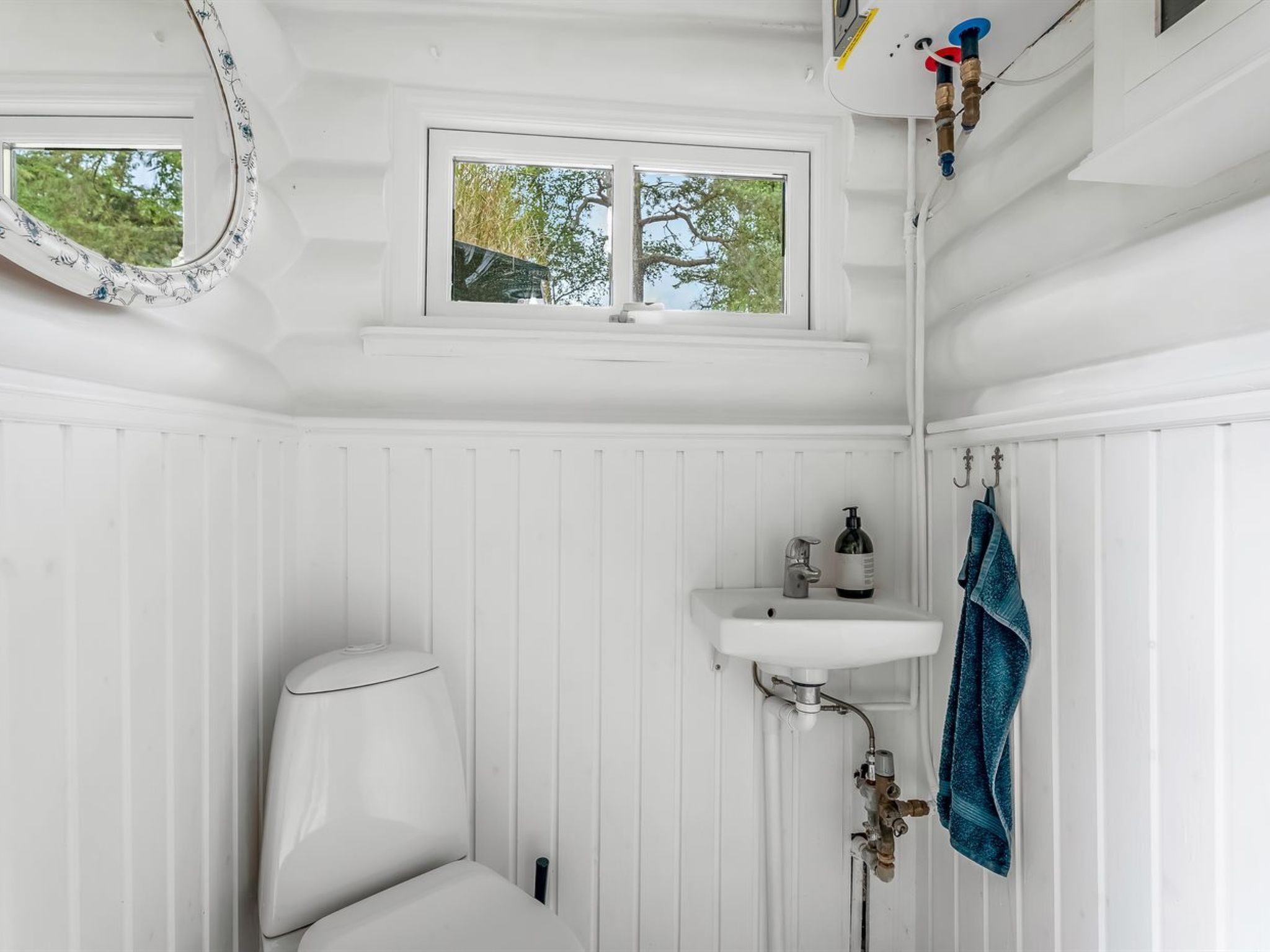 Une salle de bain blanche avec des toilettes, un lavabo et une fenêtre.