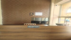 A reception desk with a 'RECEPTION' sign, a mirror, and a window with a view. - Hotel Karni Fort (Kuchaman)
