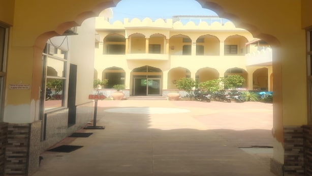A building entrance with a covered walkway, multiple arches, and potted plants. - Hotel Karni Fort (Kuchaman)