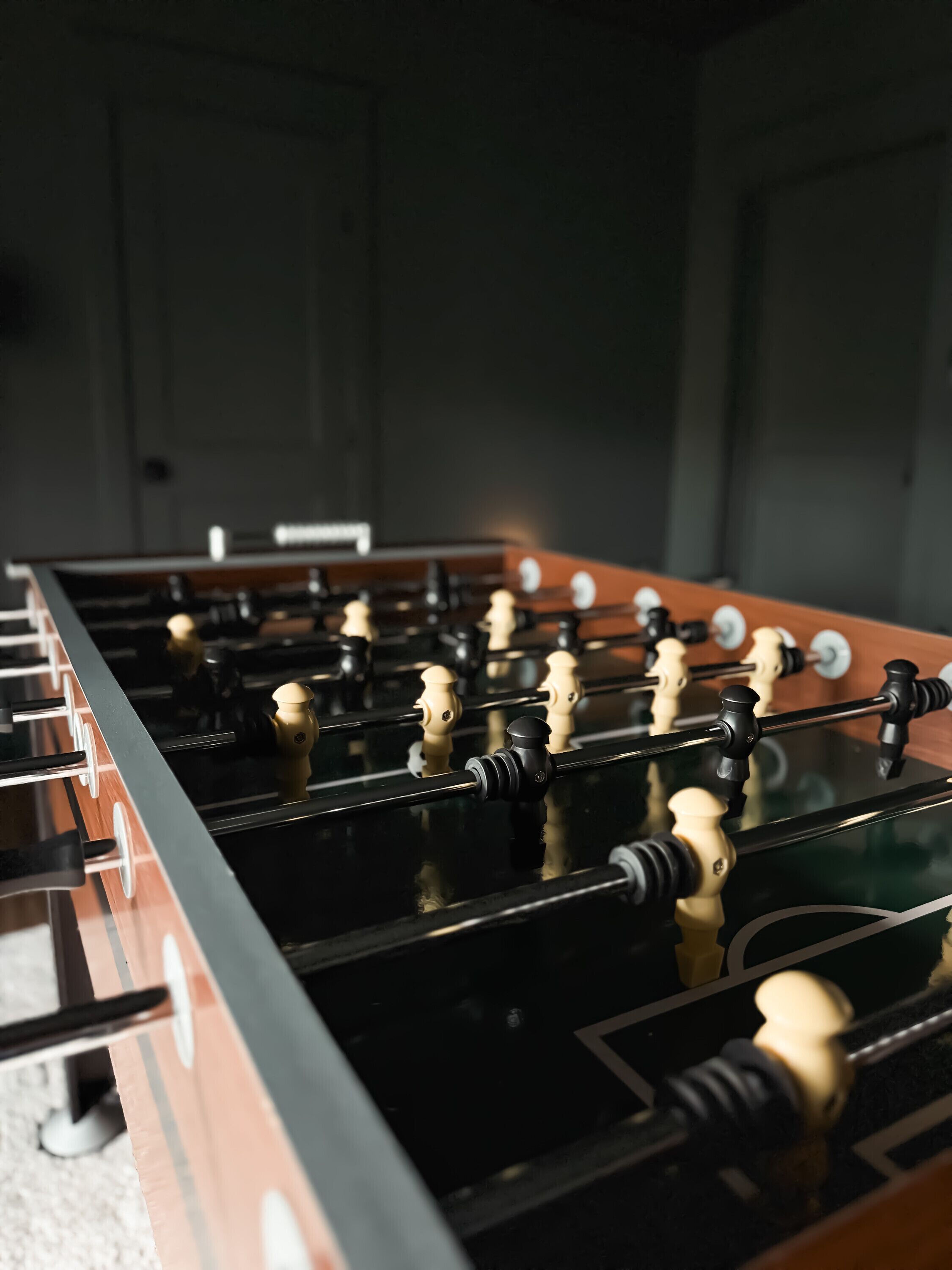 A close-up of a foosball table with a reflective surface and metallic rods.