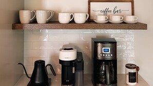 A kitchen with a coffee bar setup, including a coffee maker, cups, and a sugar container.
