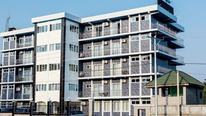A multi-story hotel with balconies, air conditioning units, and a small adjacent structure.