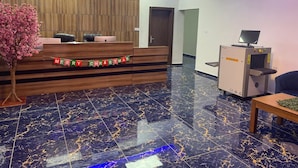 A reception desk with a Christmas banner, a wooden panel wall, a marble floor, and a small table with a plant.