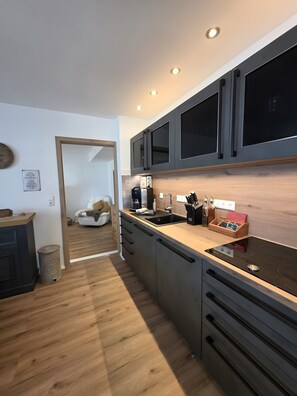 A modern kitchen with dark cabinets, a wooden countertop, and a black stovetop.