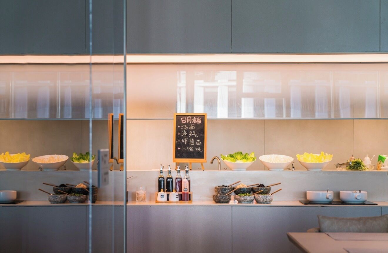 A modern kitchen with a glass partition, various bowls of food, and condiments on the counter.