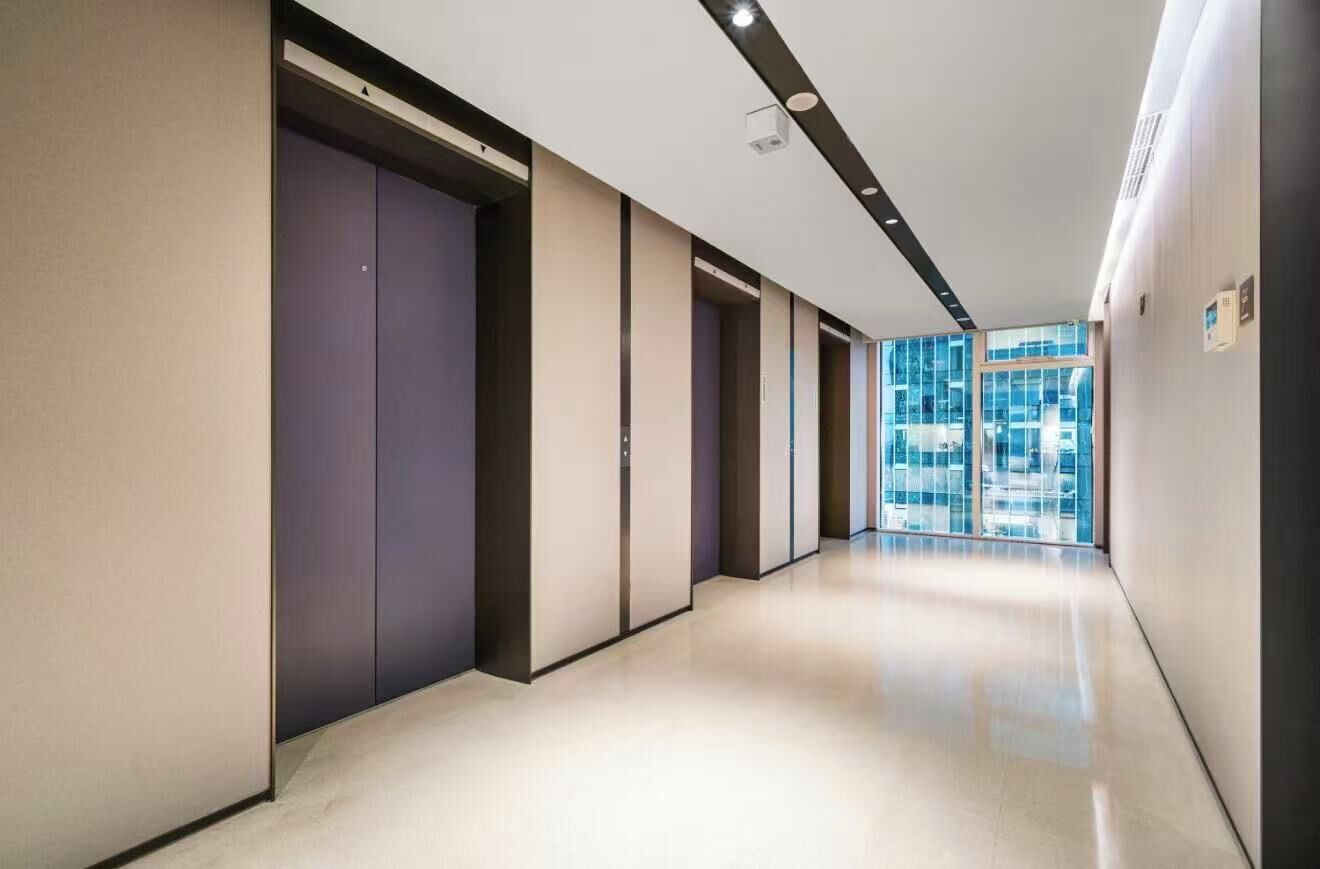 A modern hallway with a series of doors, recessed lighting, and a view of a building through large windows.