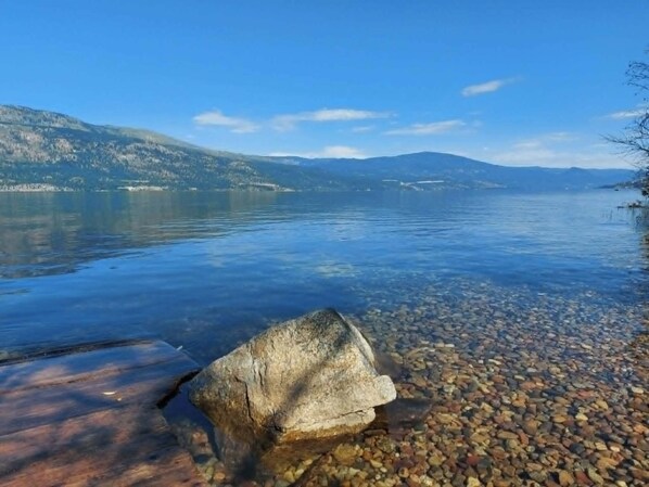 A clear lake with a rocky shoreline and distant mountains.