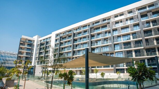 Un hotel moderno con varios pisos, un patio central con piscina y abundante vegetación alrededor.