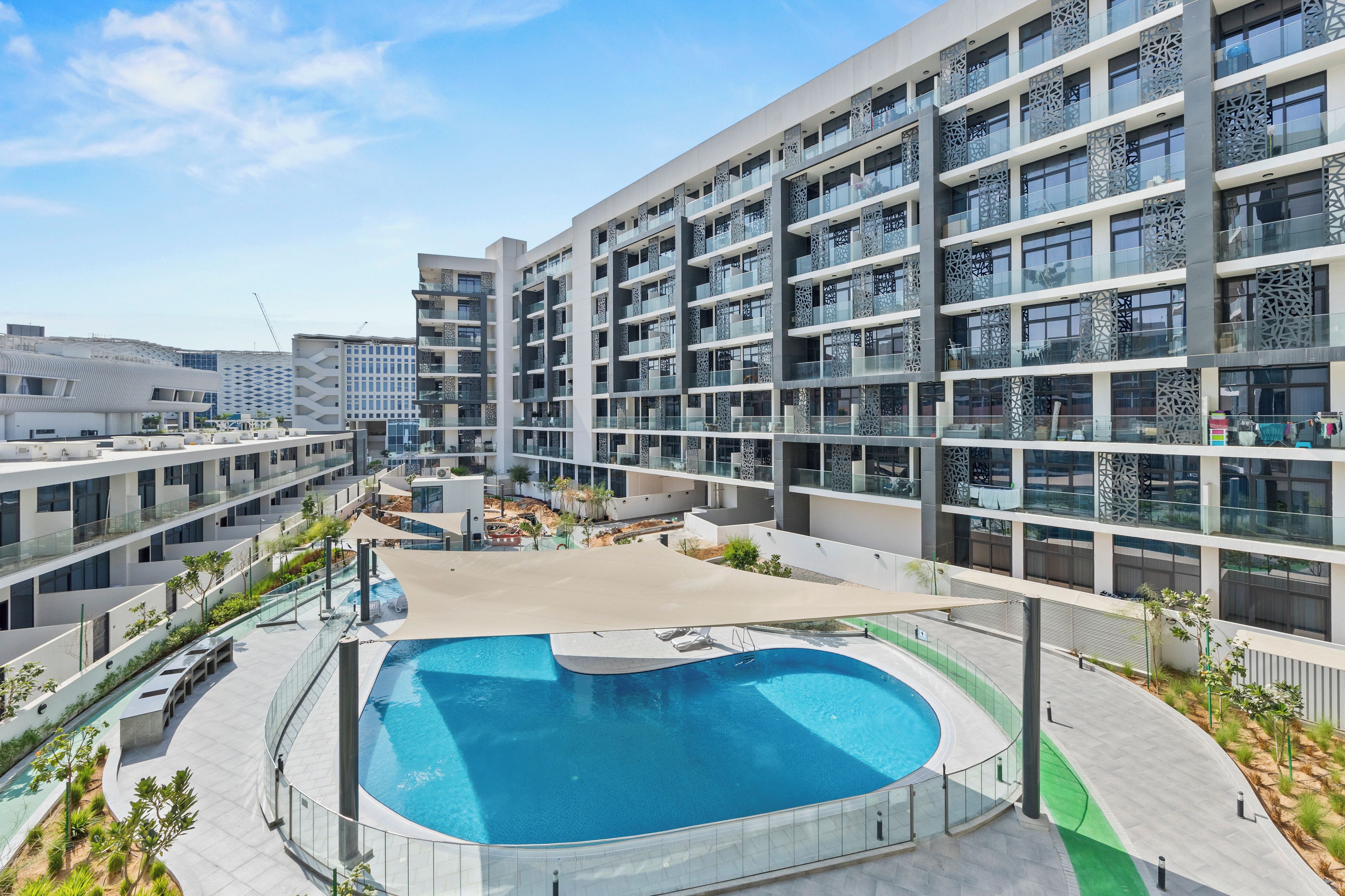 A modern multi-story building with a central swimming pool surrounded by a covered patio area.