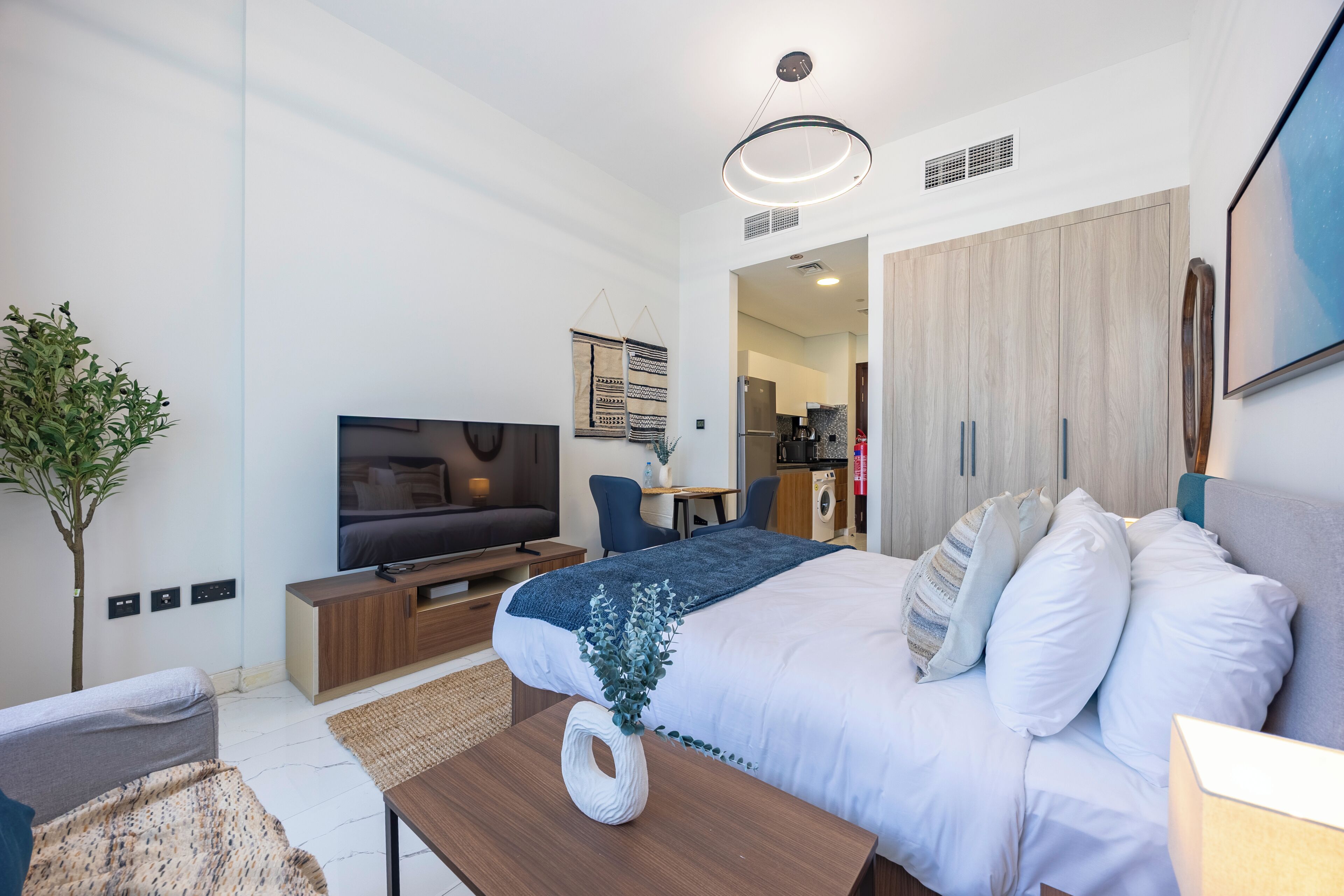 A modern bedroom with a bed, TV, and a small desk area.