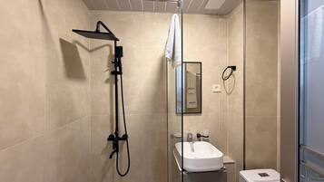 A modern bathroom with a glass-enclosed shower, a white sink, and a towel hanging on a rack.