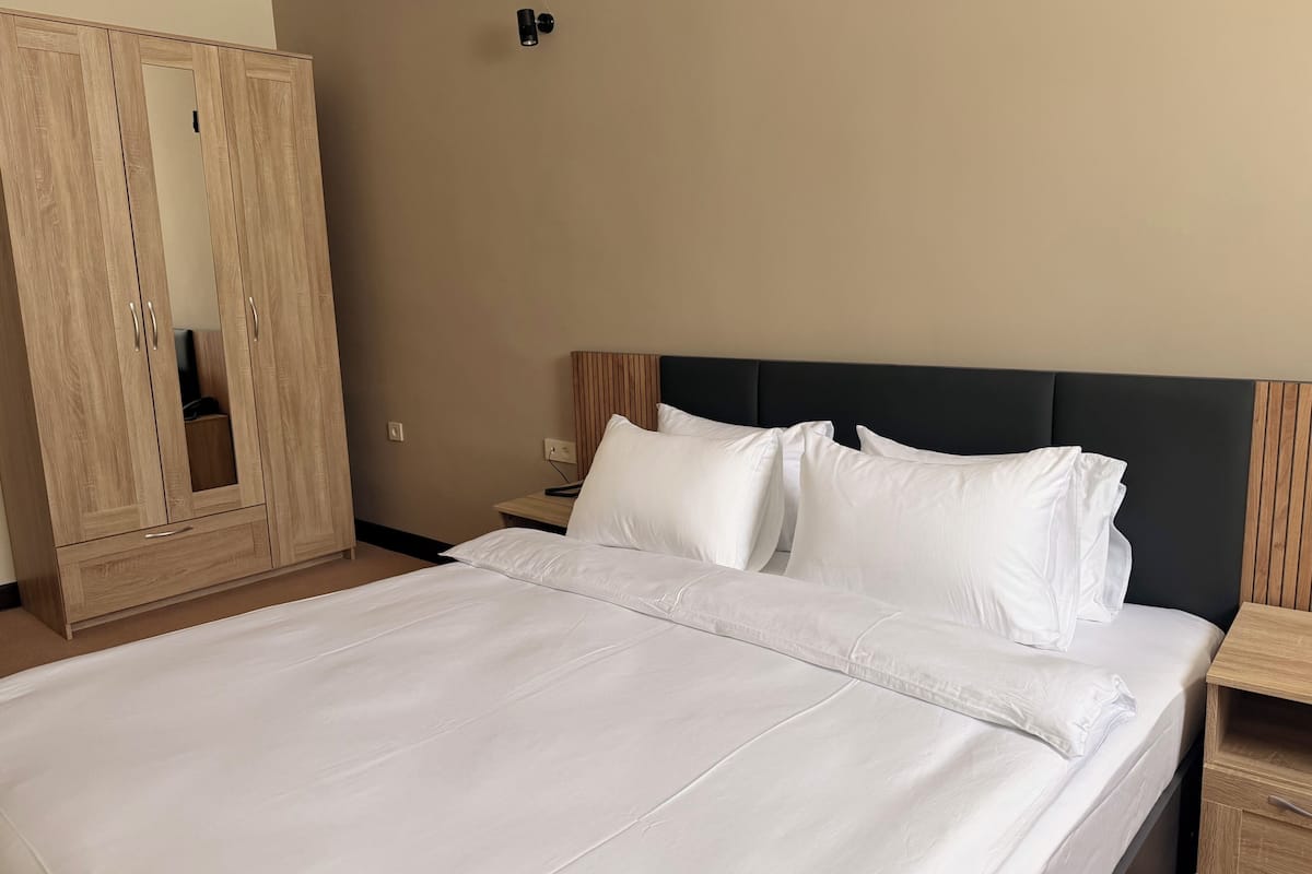 Une chambre d’hôtel avec un grand lit, une armoire en bois et une table de chevet.