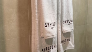 Três toalhas brancas penduradas numa parede com a inscrição 'SHELDON HOTEL'.