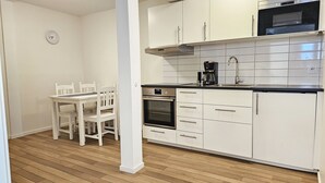 Cozinha com armários brancos, forno embutido, micro-ondas e cafeteira.