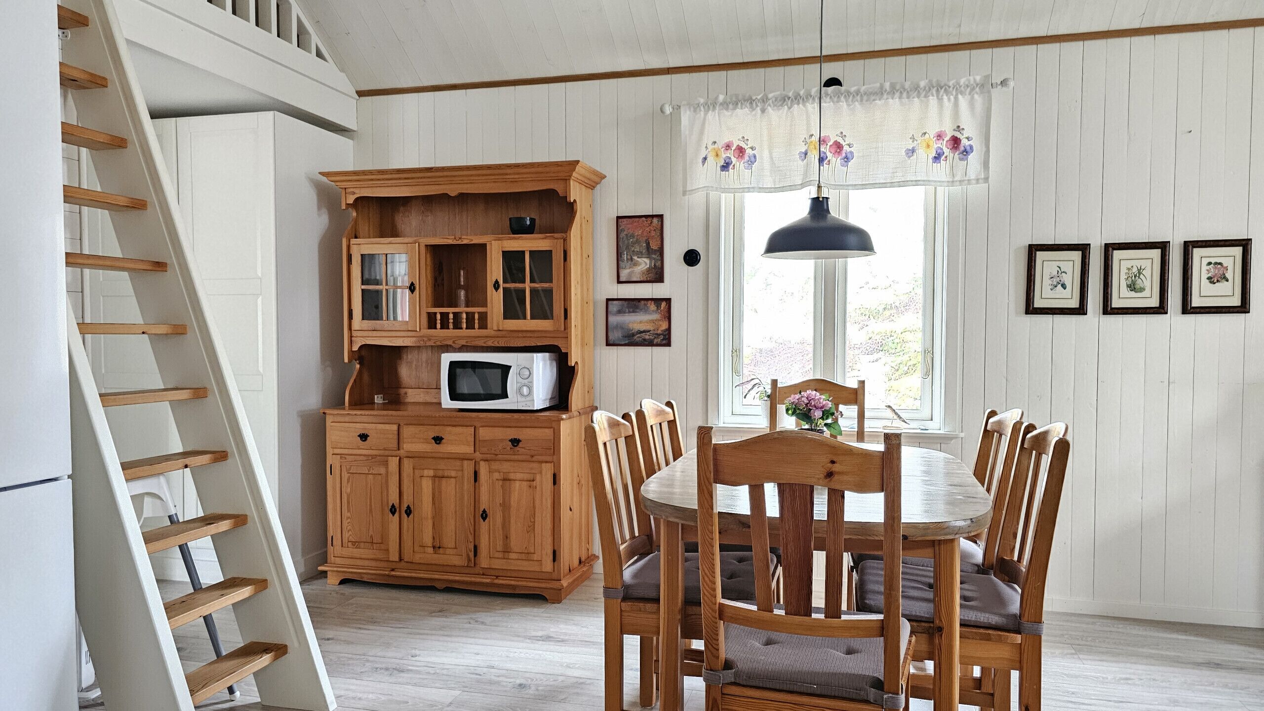 A dining area with wooden furniture, a microwave, and a staircase.