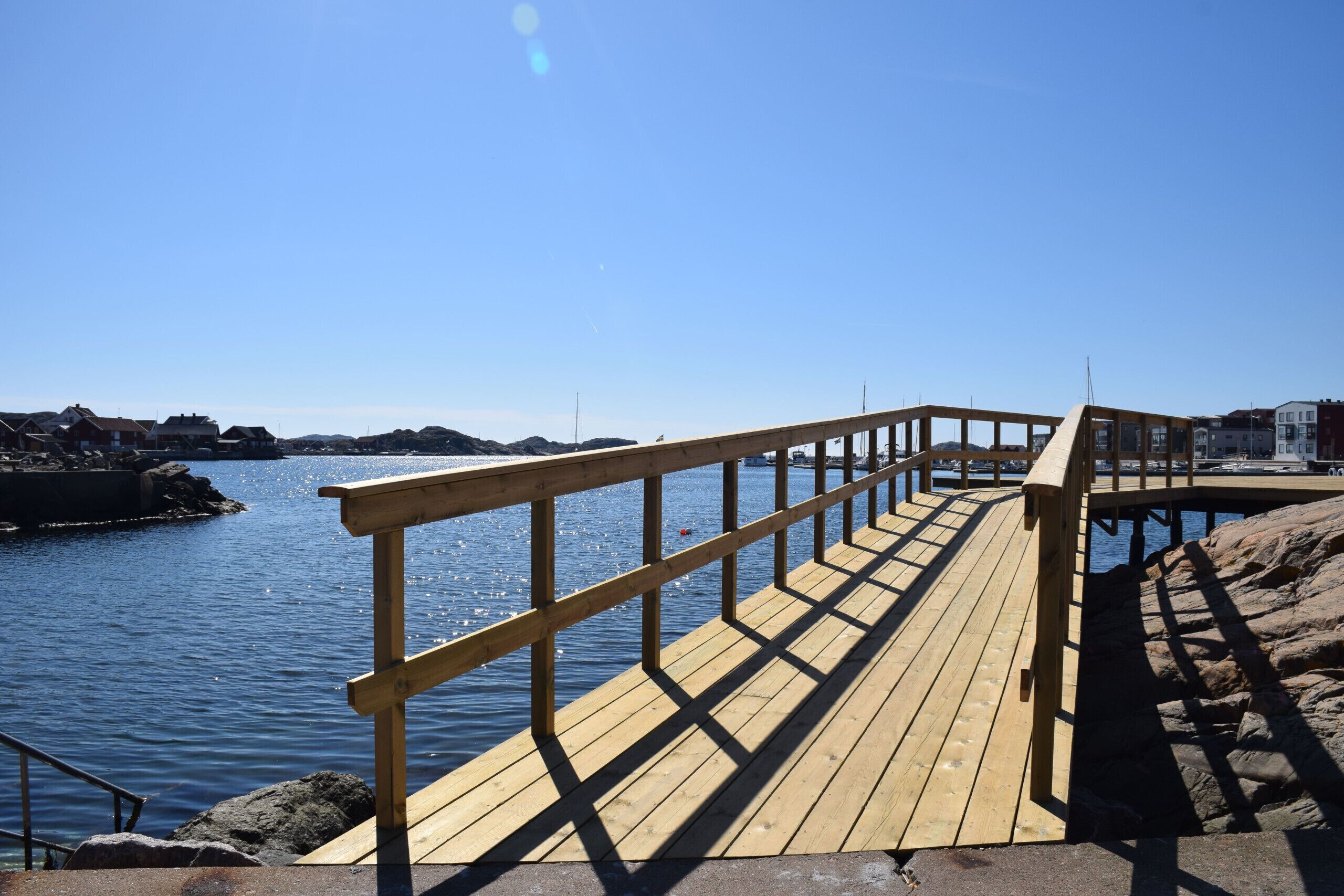 A wooden pier extending into calm water with a clear sky above.
