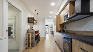 A modern kitchen with wooden cabinets, a built-in oven, and a bar area with stools.