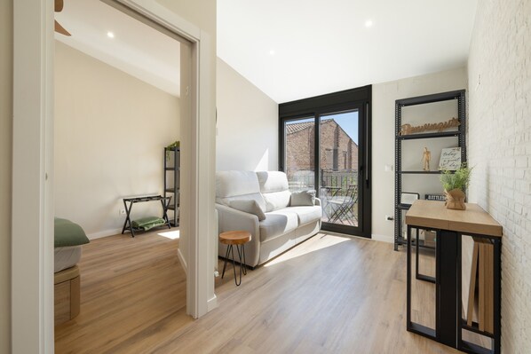 A modern living room with a white sofa, a small wooden table, and a black metal shelf.