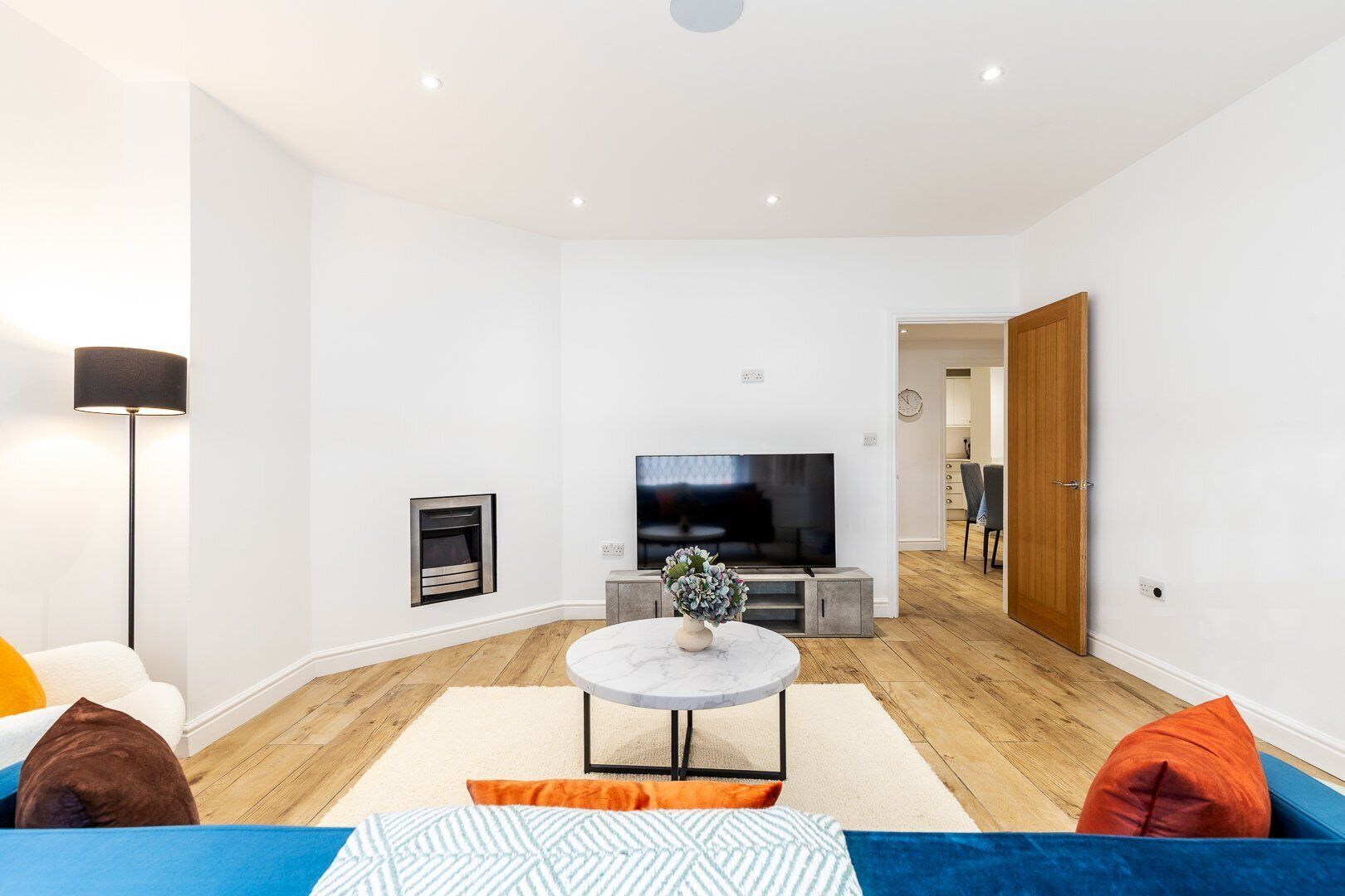 Un salon moderne avec un téléviseur à écran plat, une cheminée et un canapé.