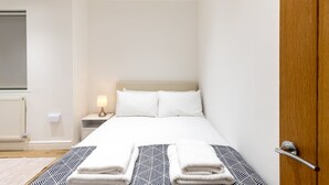 Ett hotellrum med en säng, en sänglampa och en dörr.