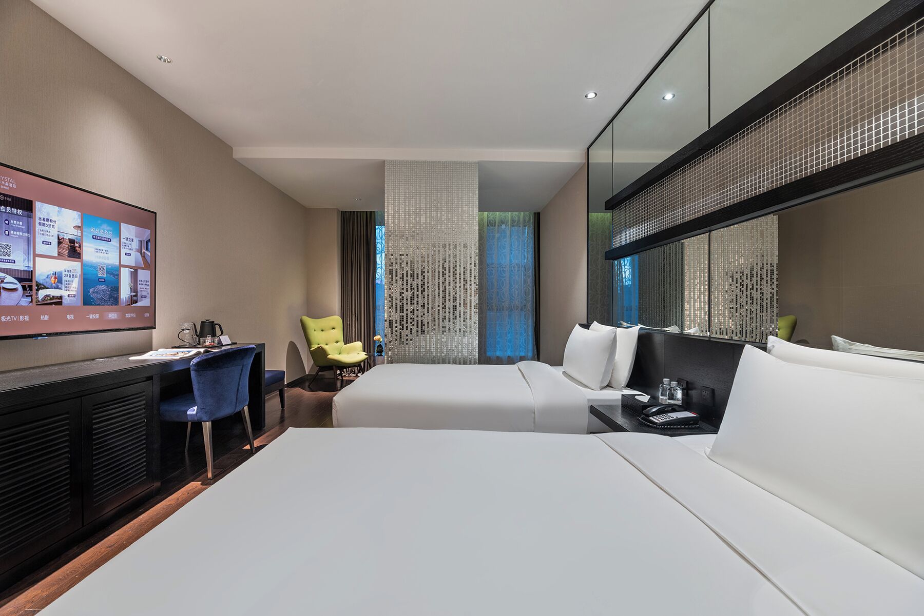 A hotel room with a bed, a desk with a computer, a chair, and a TV on the wall.