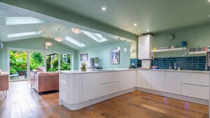 A spacious kitchen with a central island, white cabinetry, and a view of a lush garden through large sliding doors.