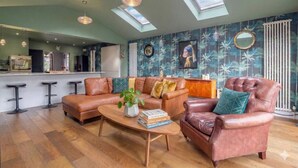 A spacious living area with a high ceiling, a kitchen in the background, and a large skylight.