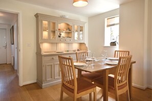 A dining area with a wooden table set for four, surrounded by wooden chairs.