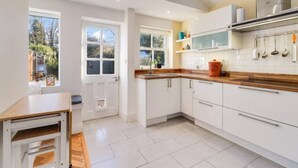 Una cocina moderna con armarios blancos, encimera de madera y un ventanal amplio.