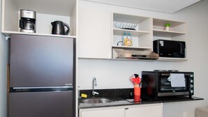 Una cucina compatta con frigorifero, microonde, forno tostatutto e un piccolo lavandino.