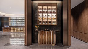 A modern lobby with a central display of bottles, a reflective floor, and a wooden reception desk. - Crystal Hotel Hangzhou Xixigu Tianmushan (Hangzhou)