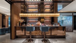 A bar area with two stools, a bartender, and shelves of bottles. - Crystal Hotel Hangzhou Xixigu Tianmushan (Hangzhou)
