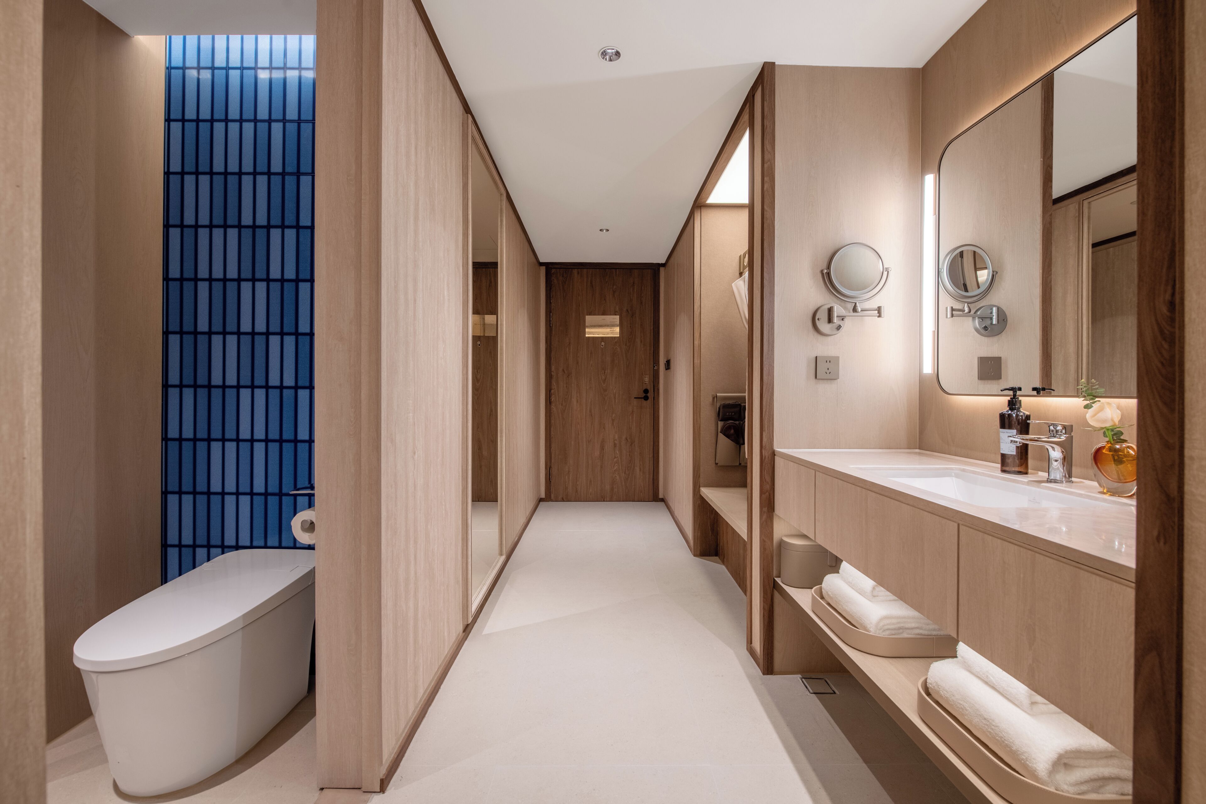 Un baño moderno con inodoro, lavamanos con espejo y pared de azulejos azules.
