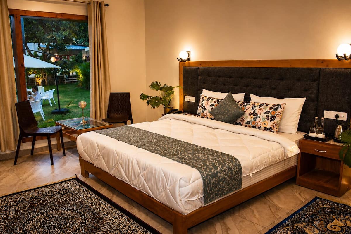 Une chambre à coucher avec un grand lit, une table de chevet, une chaise et une vue sur l’extérieur.
