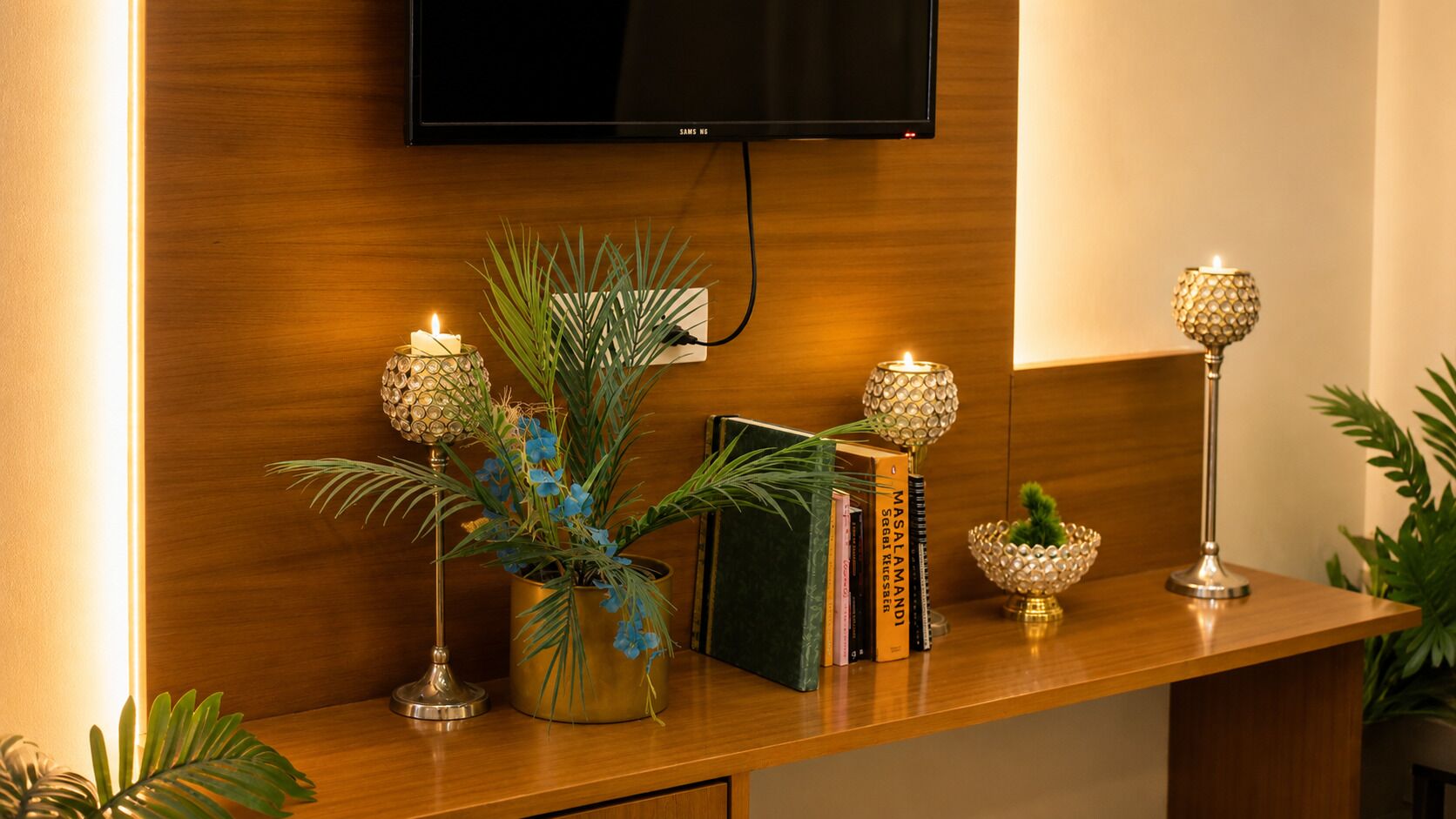 A wooden console table with decorative lamps, a potted plant, and books.